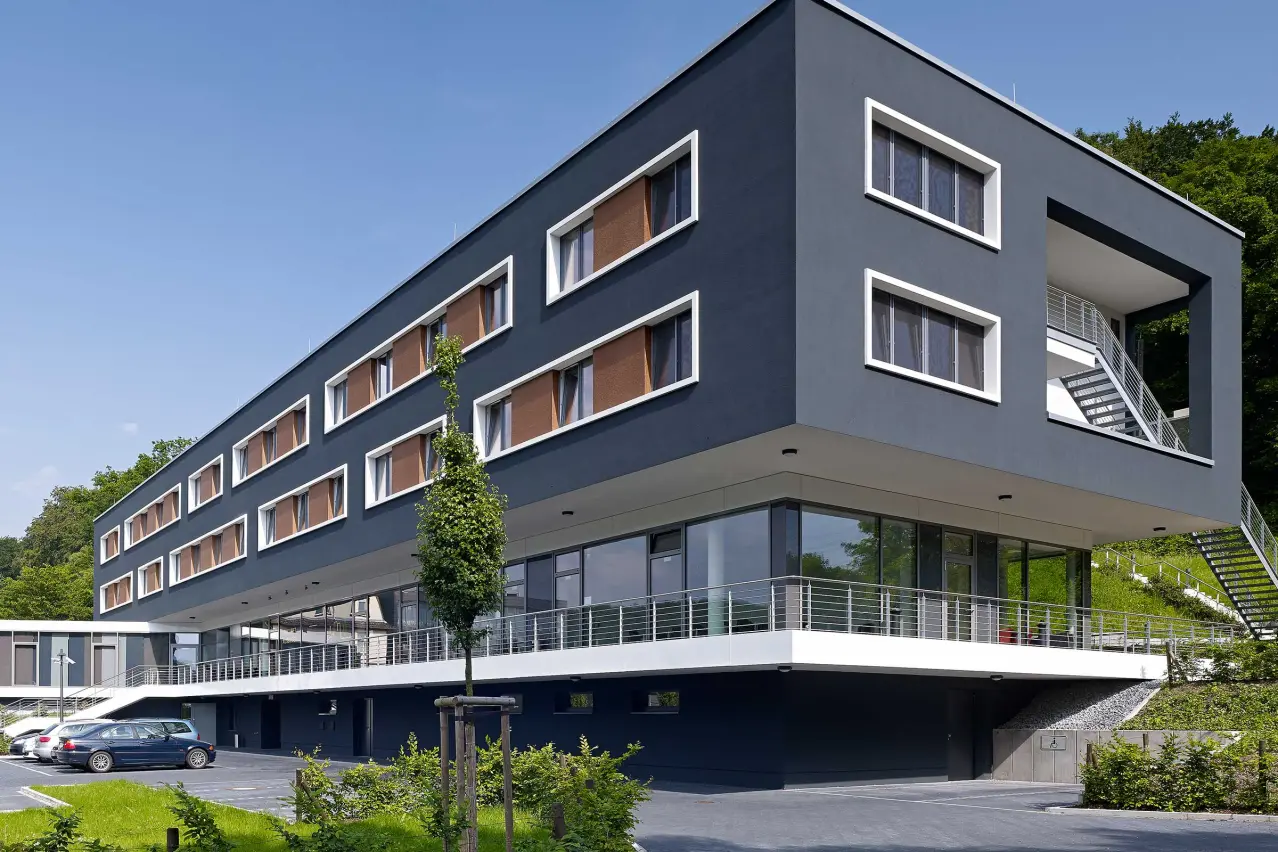 Clădire de locuințe cu fațadă termoizolată închisă la culoare, finisată cu elemente StoDeco
