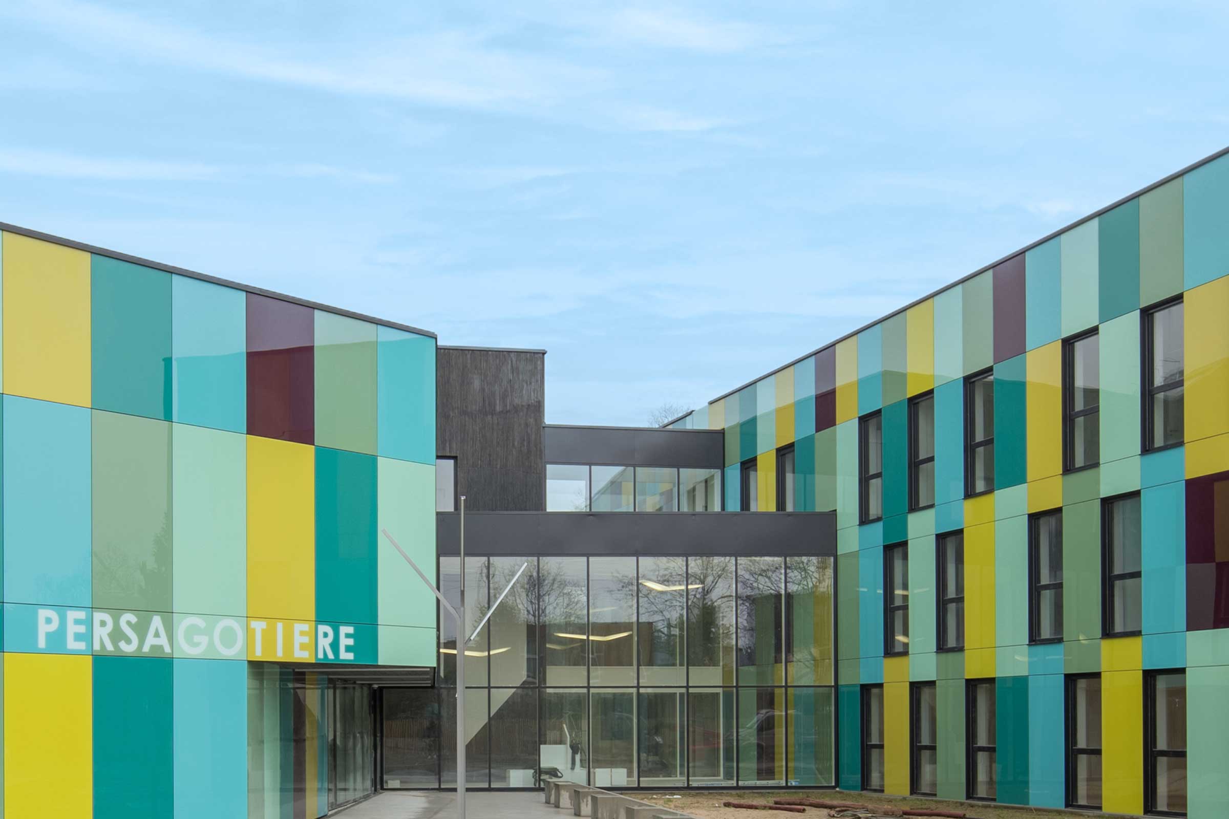 Fațadă ventilată cu panouri de sticlă în albastru, verde și galben – StoVentec Glass