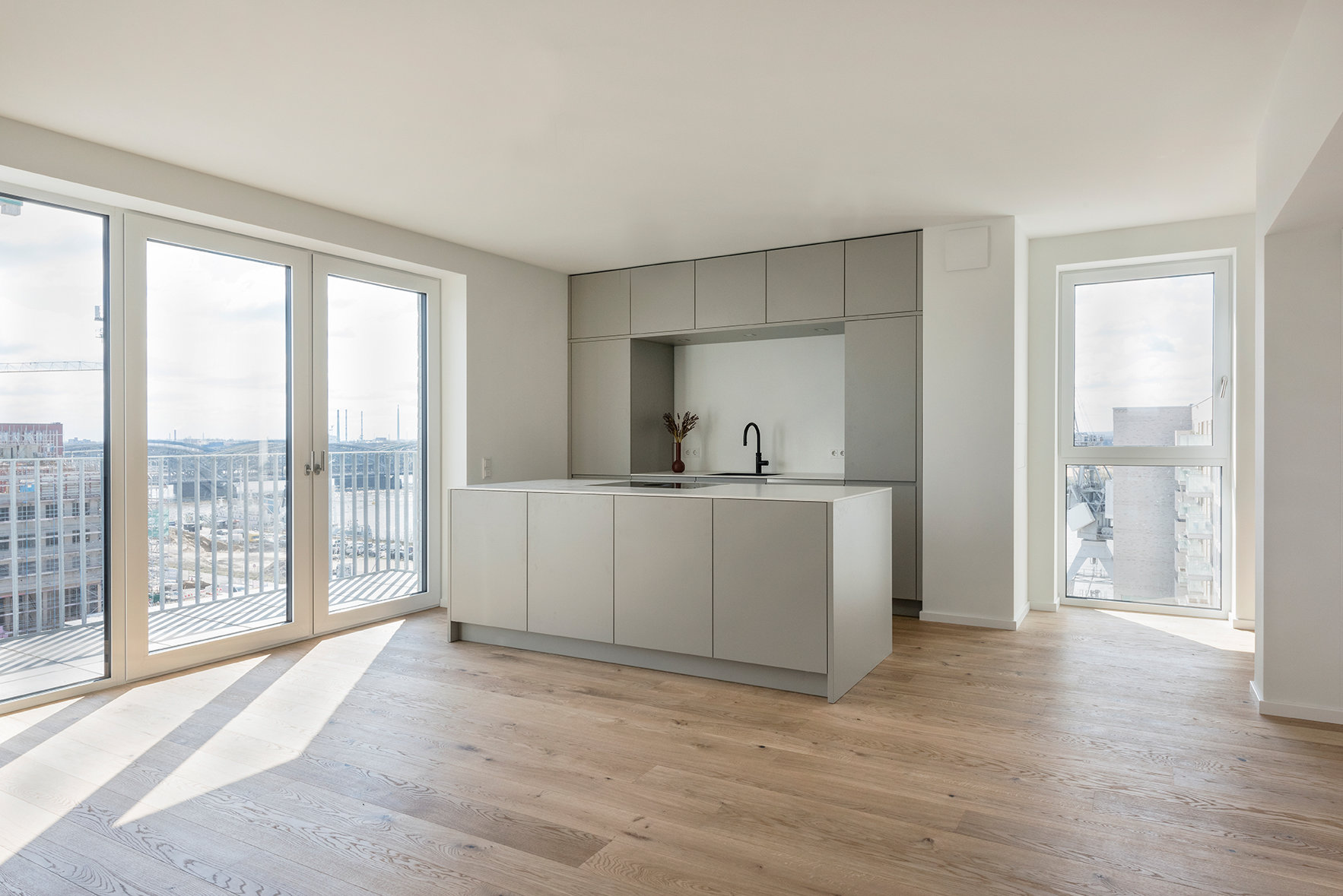 Interiorul unui apartament de la etaj, cu bucătărie deschisă și ferestre înalte